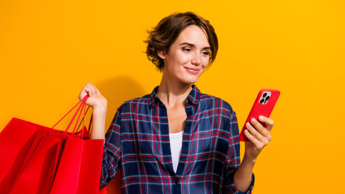 Woman holding shopping bags and looking at her phone
