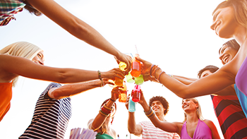 Group of people standing in a circle clinking drink glasses together