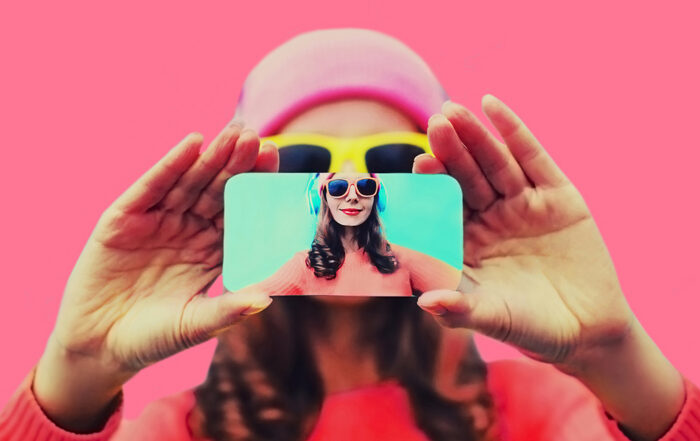 Close up of person stretching hands to take selfie with phone on pink background