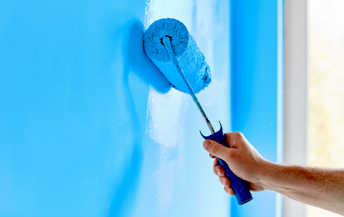 Hand painting a wall blue with a roller