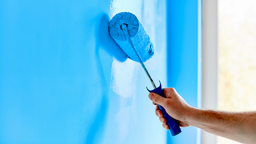 Hand painting a wall blue with a roller