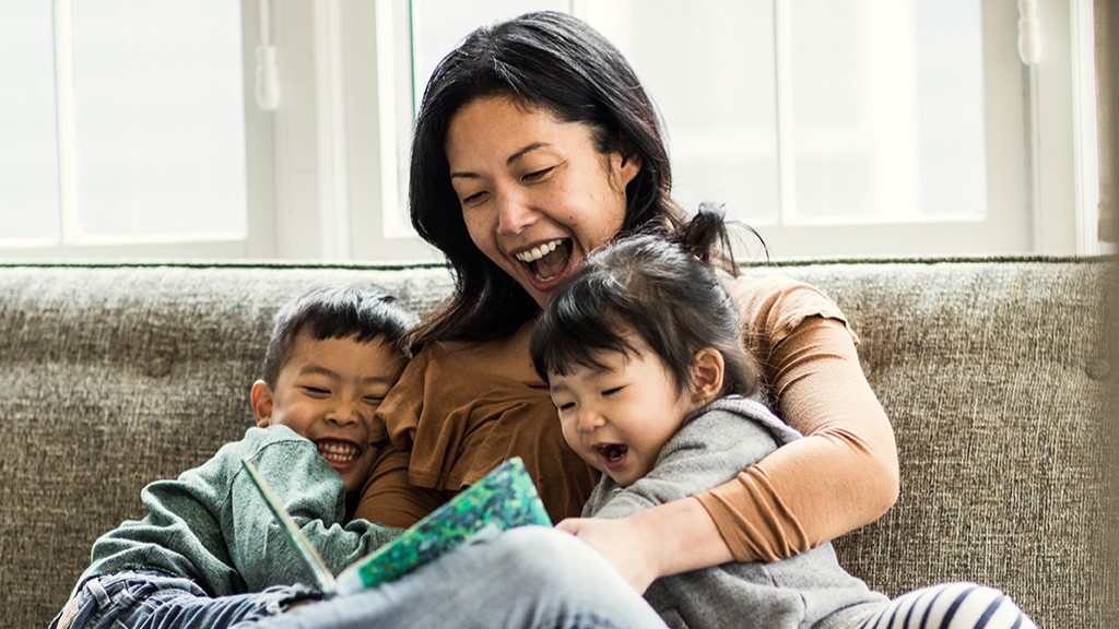 woman reading book to two kids