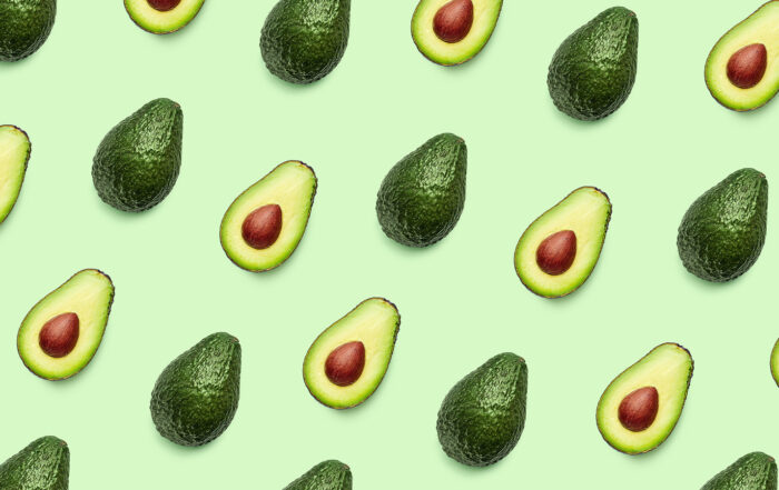 Avocados facing both ways in a diagonal pattern with a light green backgrounf