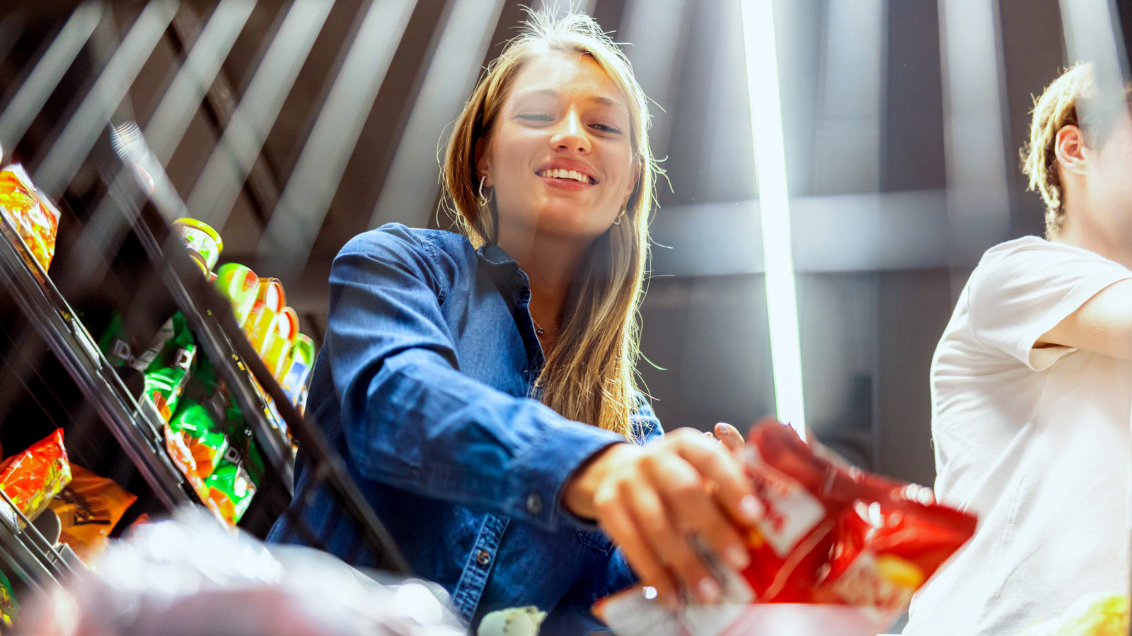 Person placing consumer packaged goods into their shopping cart