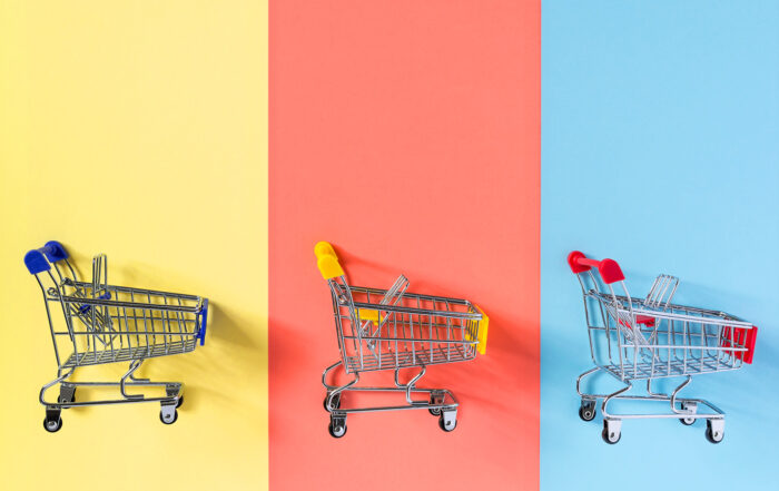 Empty supermarket shopping trolley cart on colorful yellow, red and blue background.