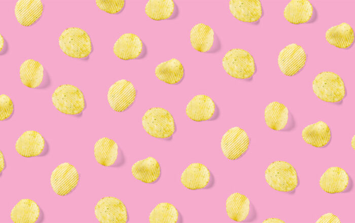 Background made from Potato chips on pink background flat lay