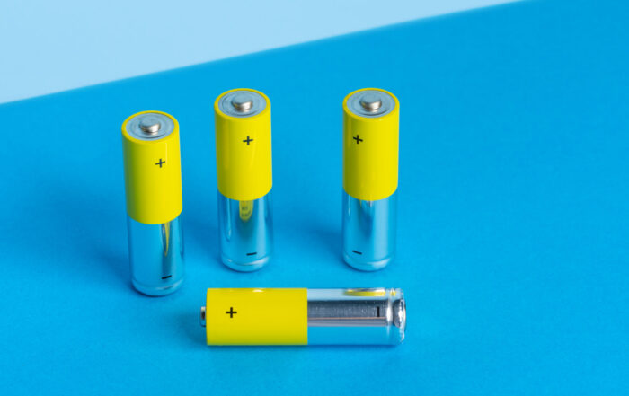 Elevated view of four yellow batteries on a blue colored background