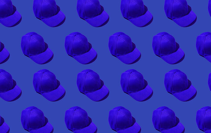 Pattern of blue baseball caps on blue background