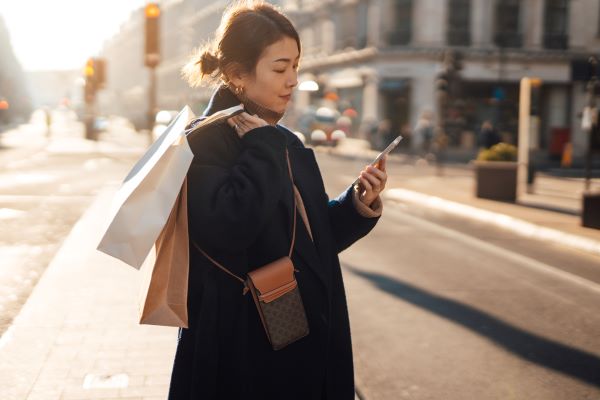 Sarah walking along a street while browsing online via her phone