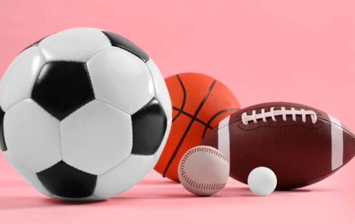 Many different sports balls on pink background