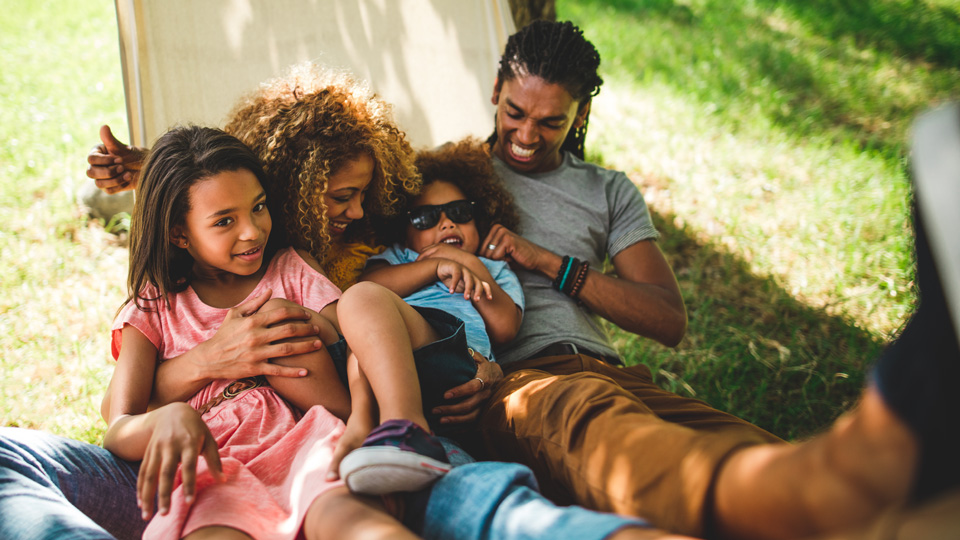 Family lying in a hammock together outside